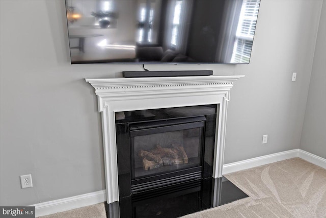 detailed view of carpet, a fireplace with flush hearth, and baseboards