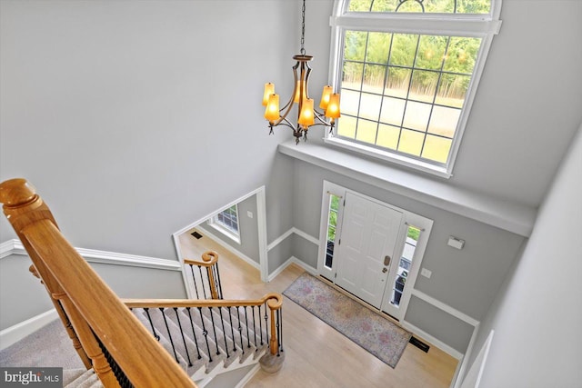 entryway featuring a chandelier, a high ceiling, wood finished floors, and baseboards