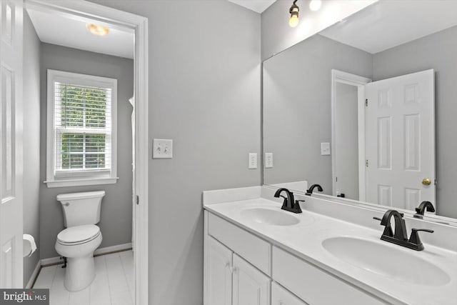full bathroom with toilet, double vanity, and baseboards