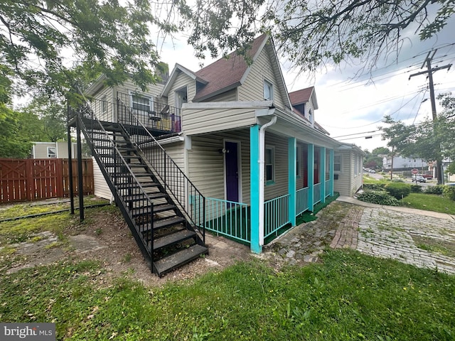 exterior space featuring fence, a shingled roof, and stairway