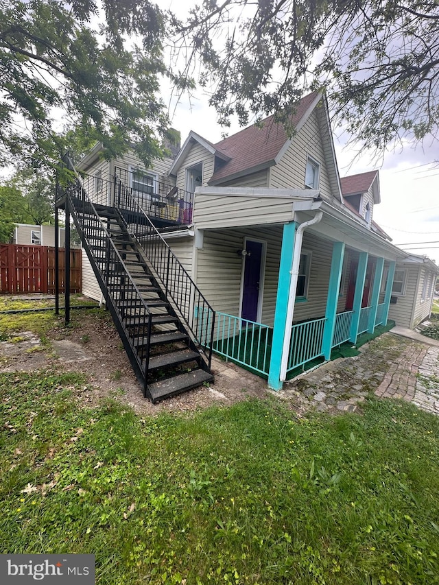 view of property exterior featuring stairway, fence, and covered porch