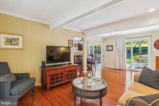 living area featuring beam ceiling, plenty of natural light, ornamental molding, and wood finished floors