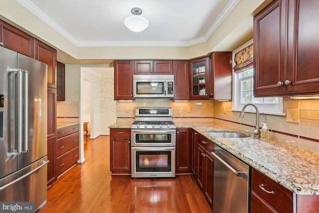 kitchen featuring appliances with stainless steel finishes, dark brown cabinets, a sink, glass insert cabinets, and dark wood-type flooring
