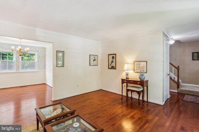 sitting room featuring a chandelier, ornamental molding, wood finished floors, and stairway