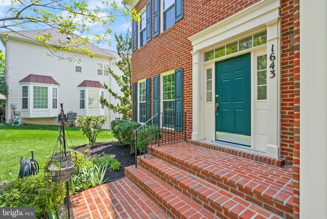 doorway to property with a lawn and brick siding