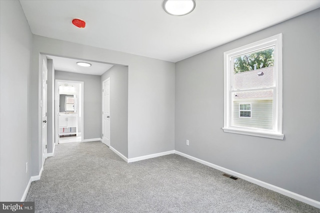 unfurnished room with visible vents, carpet, and baseboards