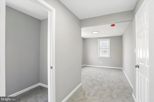corridor featuring baseboards and carpet
