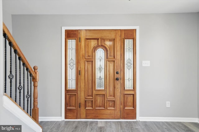 foyer entrance with baseboards, stairs, and wood finished floors