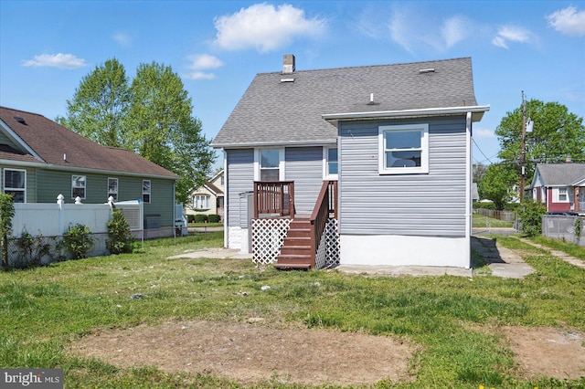 rear view of property with a yard, fence, a chimney, and roof with shingles