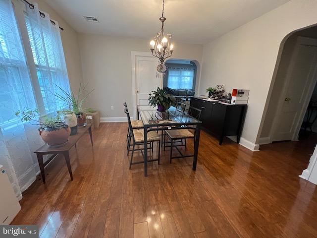 dining room with baseboards, arched walkways, a notable chandelier, and hardwood / wood-style floors