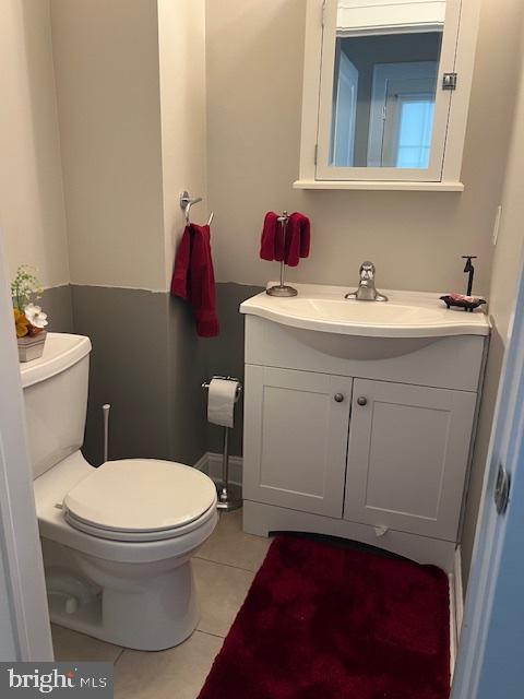 half bathroom with tile patterned floors, vanity, and toilet