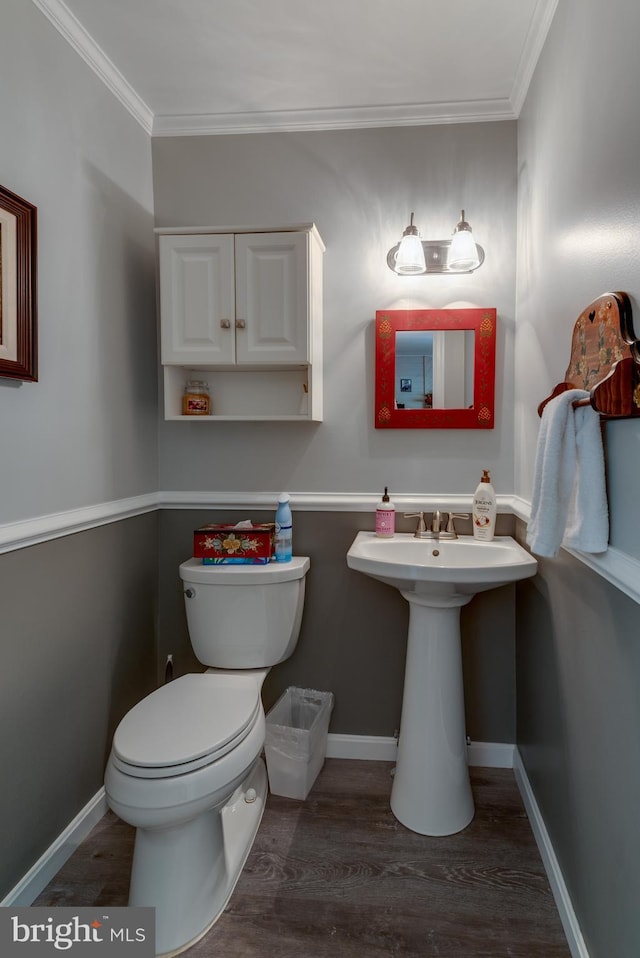 bathroom with crown molding, baseboards, wood finished floors, and toilet