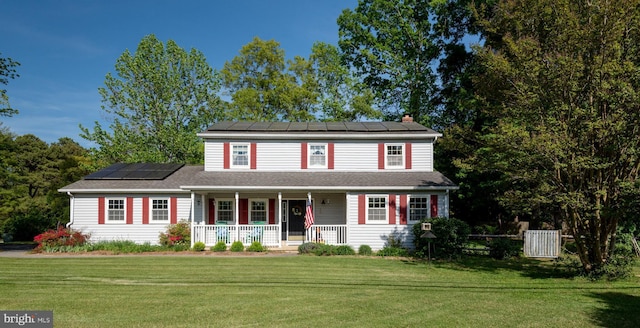 view of front of property with a porch, roof mounted solar panels, a chimney, and a front yard