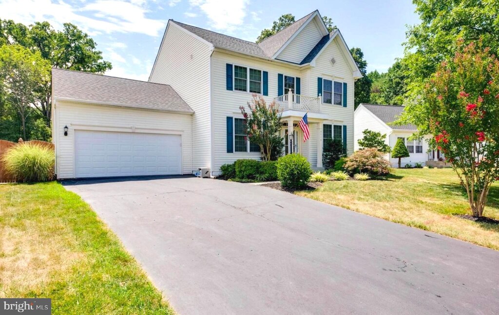 view of front of property with an attached garage, a front lawn, and driveway