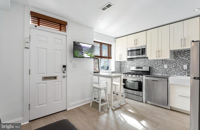 kitchen with baseboards, appliances with stainless steel finishes, visible vents, and tasteful backsplash