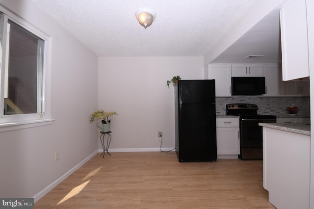 kitchen with decorative backsplash, light wood-style floors, baseboards, white cabinets, and black appliances