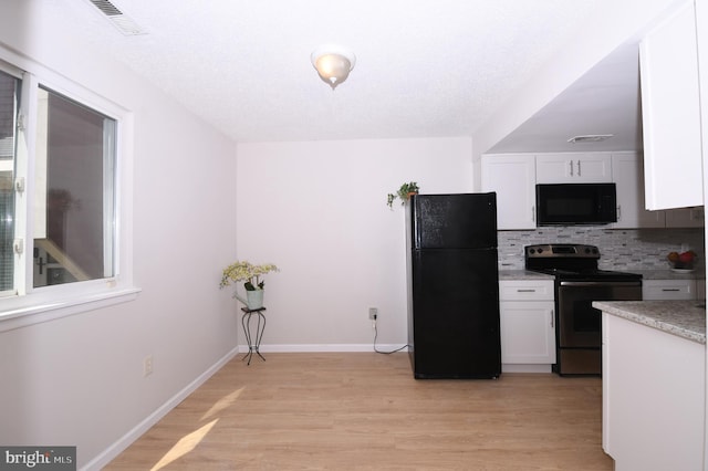 kitchen with white cabinets, backsplash, black appliances, and light wood-type flooring