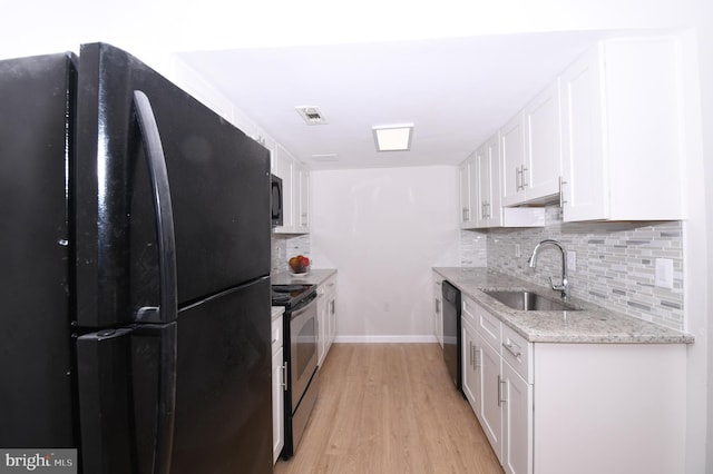 kitchen featuring decorative backsplash, visible vents, a sink, black appliances, and light wood-style floors
