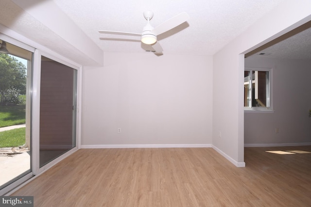 empty room featuring baseboards, ceiling fan, a textured ceiling, and light wood-style flooring