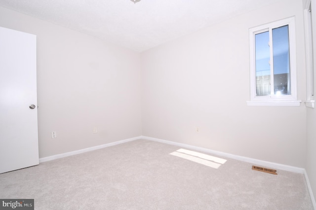 carpeted spare room with visible vents and baseboards