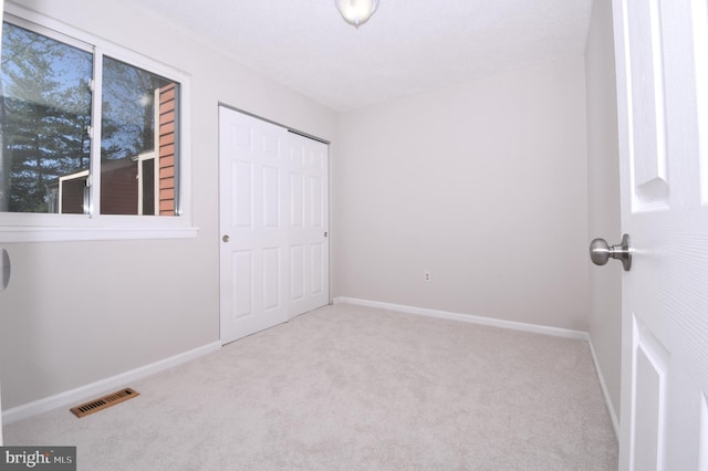 unfurnished bedroom featuring visible vents, baseboards, carpet floors, and a closet