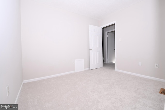 spare room with baseboards and light carpet