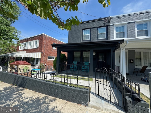 5371 Chillum Pl NE, Washington, DC 20011 - view of front facade with covered porch, a fenced front yard, brick siding, and mansard roof