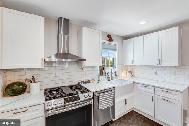 5371 Chillum Pl NE, Washington, DC 20011 - kitchen with appliances with stainless steel finishes, wall chimney range hood, light stone countertops, white cabinetry, and recessed lighting