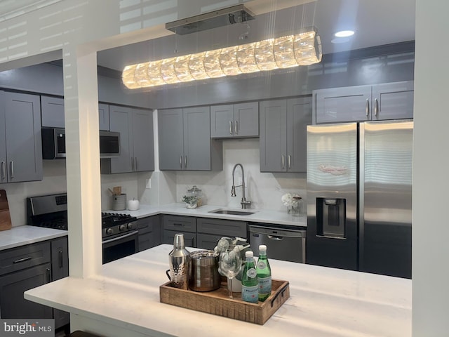 kitchen with a sink, appliances with stainless steel finishes, gray cabinets, and light countertops