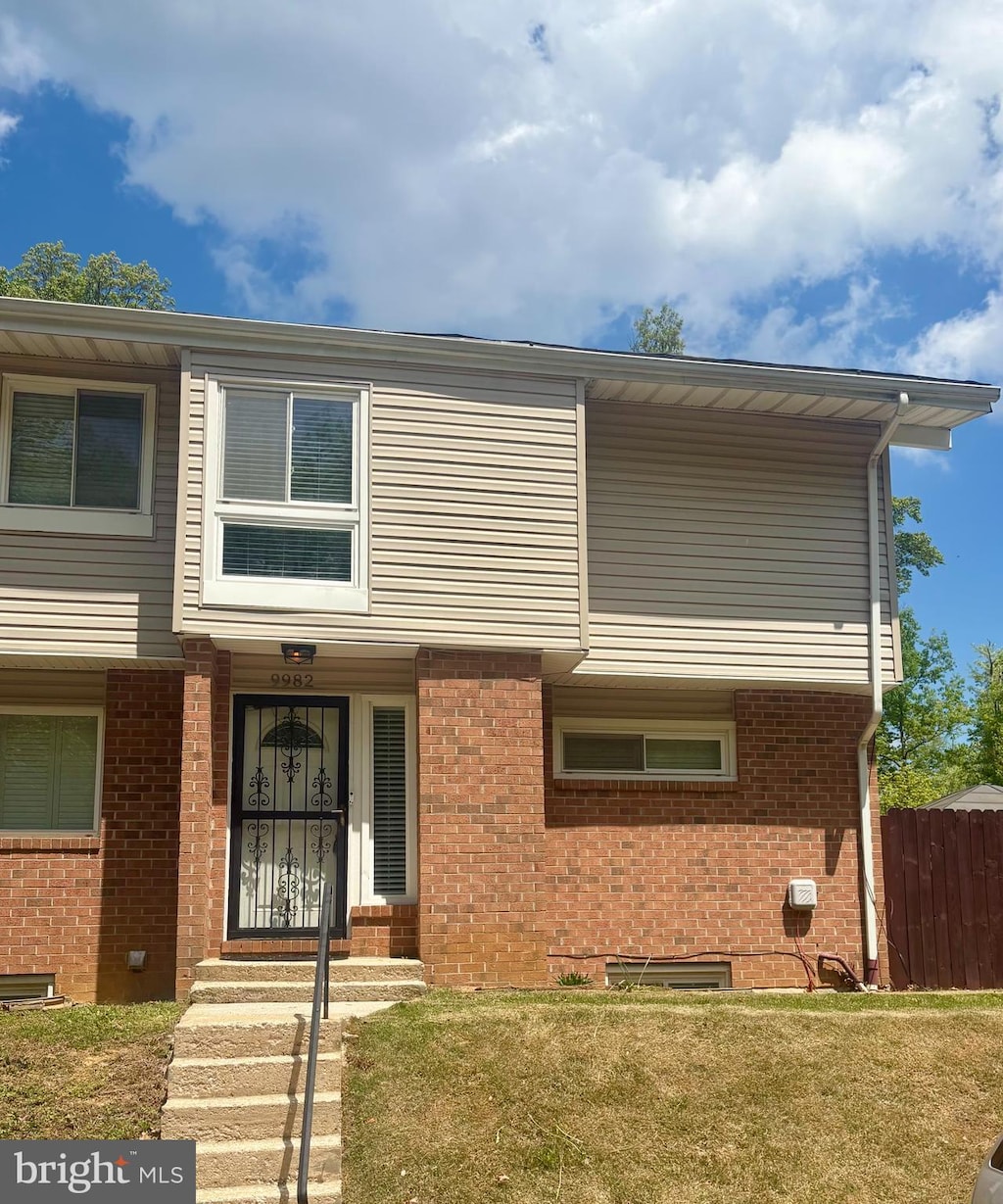 view of front of home with brick siding, a front lawn, and fence