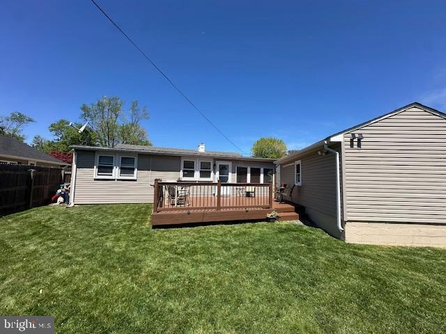 rear view of house with a yard, a deck, and fence