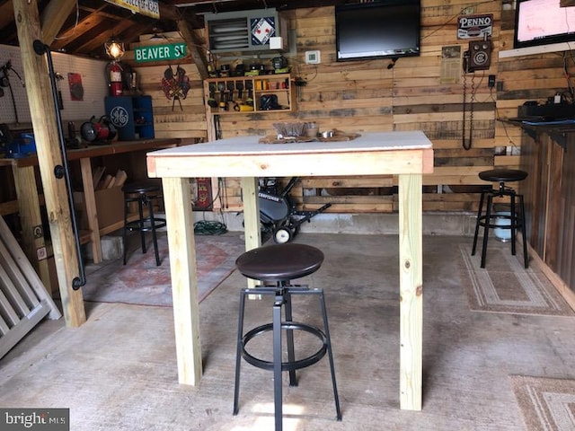 bar featuring wooden walls, a workshop area, and unfinished concrete floors