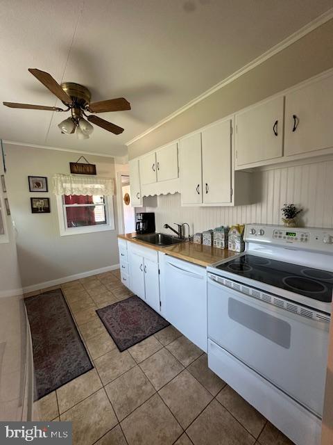 kitchen with a sink, white cabinets, light tile patterned flooring, and white appliances