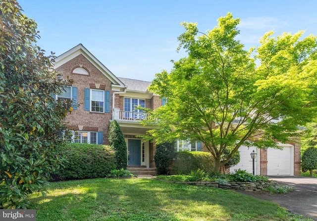 view of front of home with brick siding, a garage, a front yard, and aphalt driveway