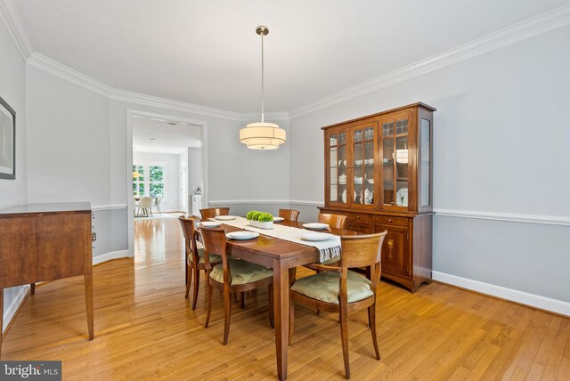 dining space featuring baseboards, ornamental molding, and light wood finished floors
