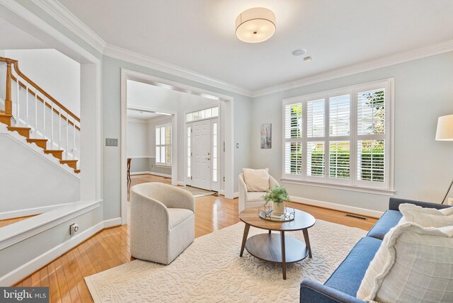 living area with visible vents, wood finished floors, stairway, baseboards, and ornamental molding