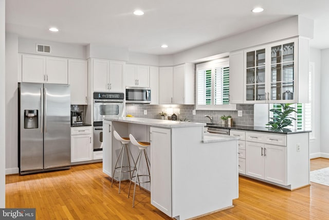 kitchen featuring backsplash, visible vents, appliances with stainless steel finishes, light wood-style floors, and white cabinetry
