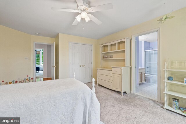 bedroom featuring ensuite bathroom, a closet, ceiling fan, and light colored carpet