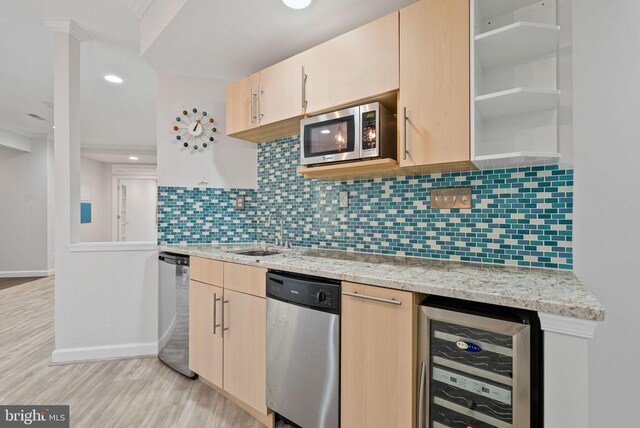 kitchen featuring backsplash, appliances with stainless steel finishes, a sink, light wood finished floors, and beverage cooler