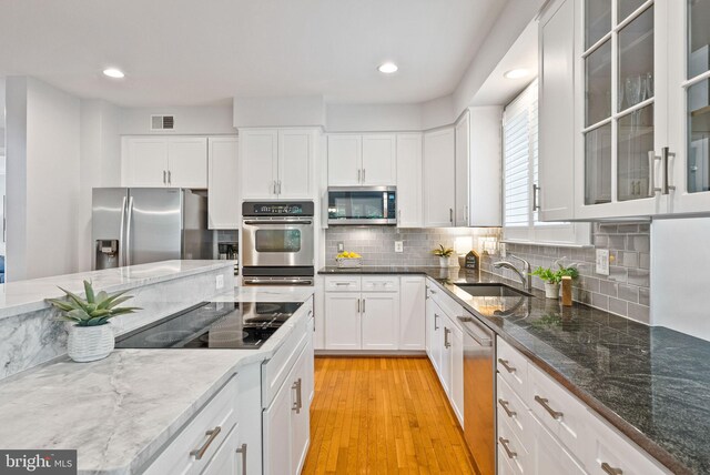 kitchen featuring a sink, stainless steel appliances, white cabinetry, light wood-type flooring, and visible vents