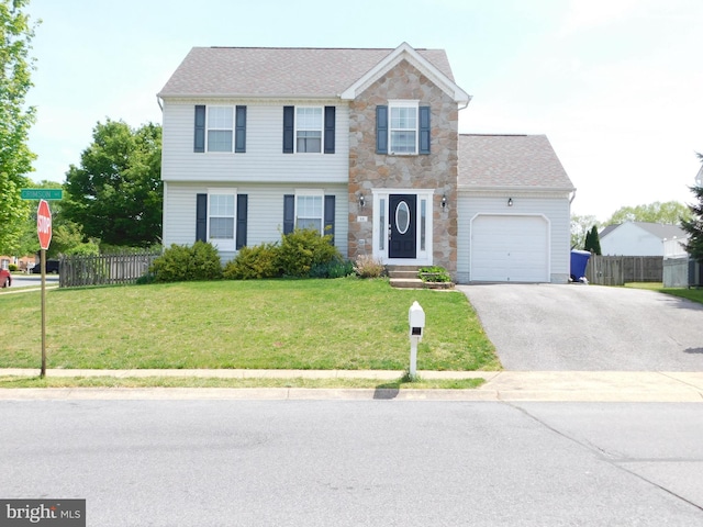 colonial home with a front lawn, aphalt driveway, fence, stone siding, and an attached garage