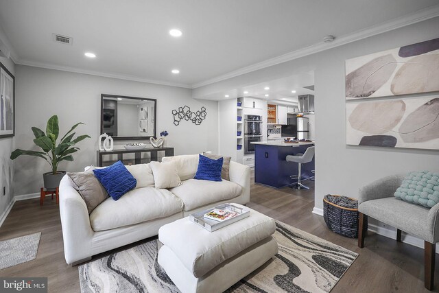 living room with crown molding, recessed lighting, baseboards, wood finished floors, and visible vents