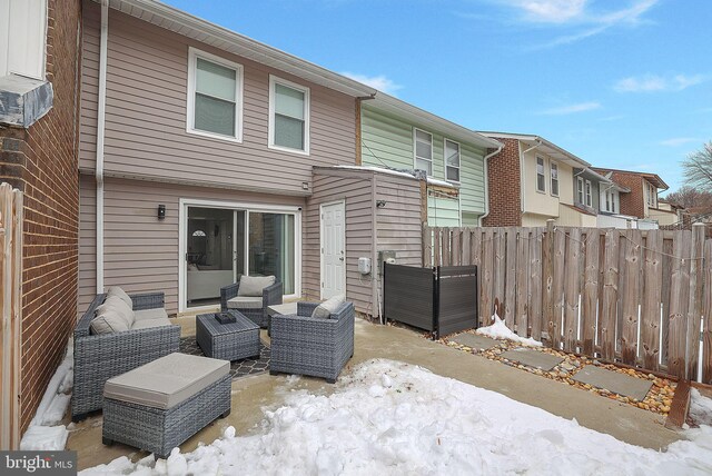 snow covered property with fence, an outdoor hangout area, and a patio area