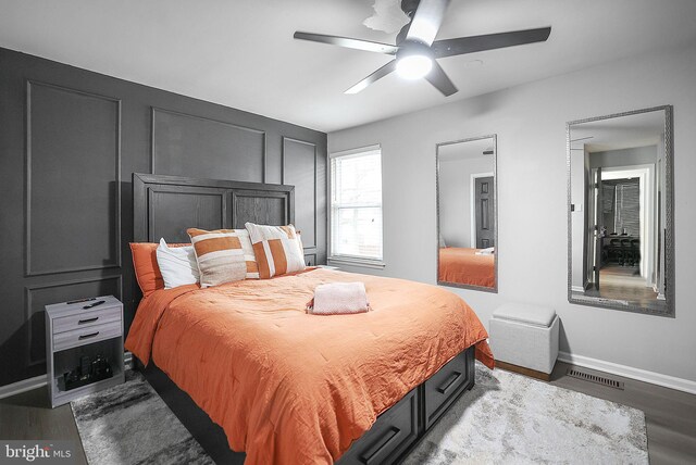 bedroom with a ceiling fan, baseboards, visible vents, and wood finished floors