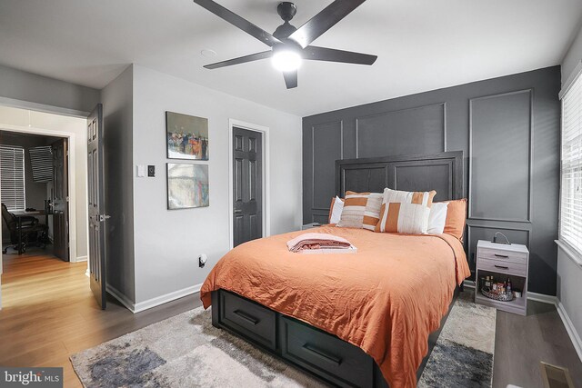 bedroom featuring baseboards, ceiling fan, wood finished floors, and visible vents