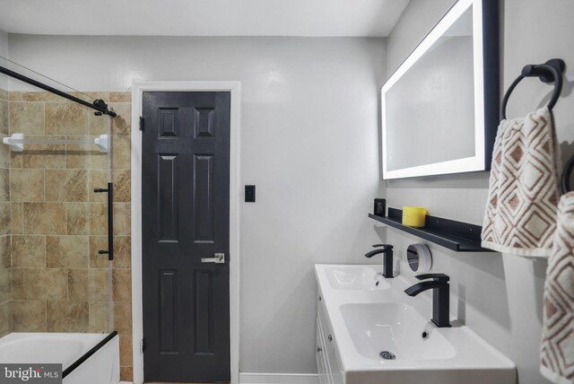 bathroom featuring a sink, baseboards, double vanity, and tub / shower combination