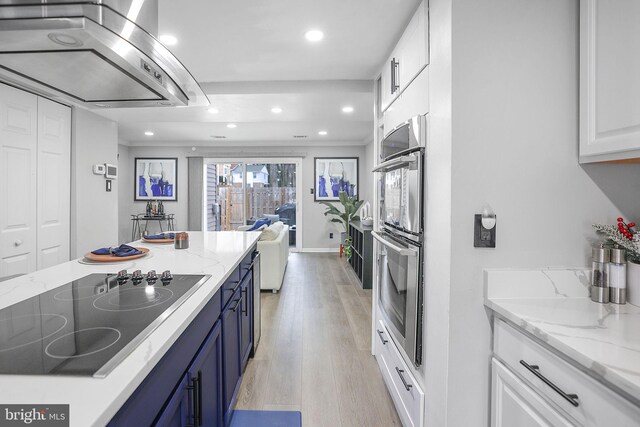kitchen with blue cabinetry, black electric cooktop, ventilation hood, white cabinets, and double oven