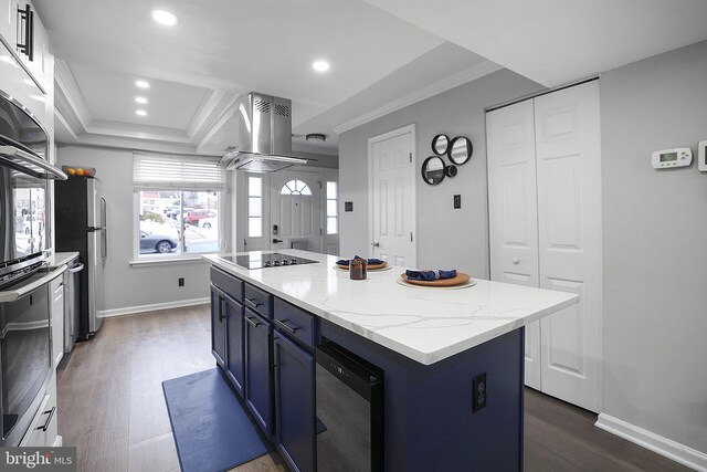 kitchen featuring dark wood-style flooring, black electric cooktop, island range hood, a tray ceiling, and blue cabinets