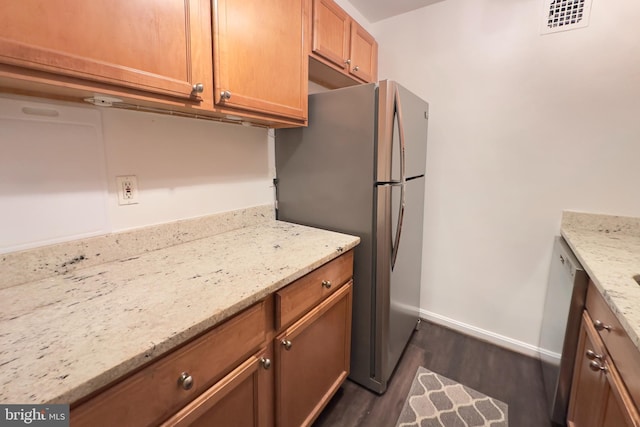 kitchen with light stone countertops, visible vents, dark wood-style floors, and baseboards