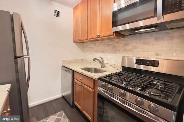 kitchen featuring baseboards, light stone counters, a sink, dark wood finished floors, and appliances with stainless steel finishes